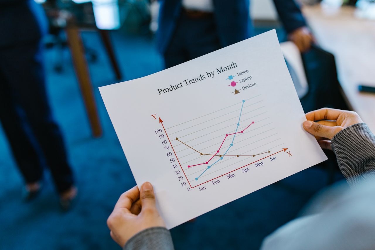 Close-up of hands holding a product trend chart in a corporate office setting.